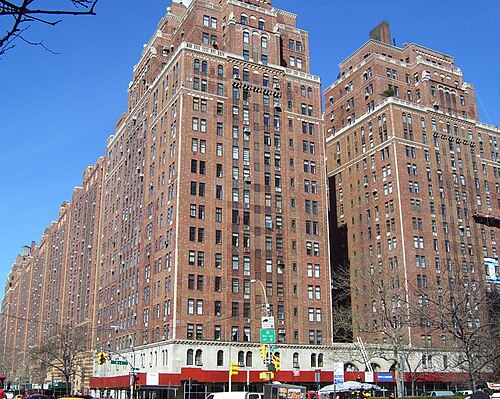 London Terrace from West 23rd Street, a brick apartment block running the length of the street with awnings and shops under it.