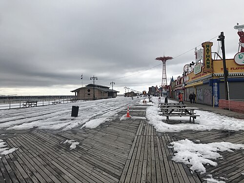 The boardwalk streaked with snow, a shuttered Nathan's stand, the off season the page describes.