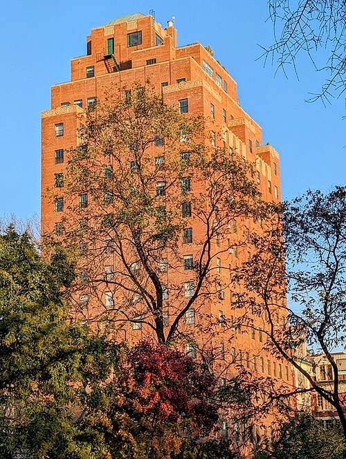 Christodora House, a sixteen story brick tower on the east side of Tompkins Square Park, seen through the trees in autumn light.