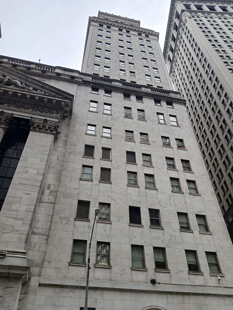 The Broad Street front of the New York Stock Exchange, looking up at the pediment and the marble tower behind it.