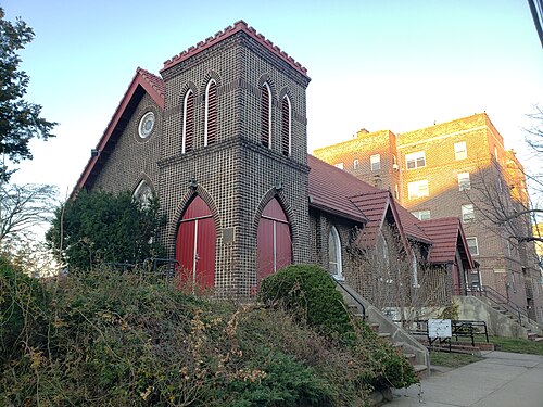 First Presbyterian Church of Forest Hills, a patterned brick church tower with red tile trim next to an apartment building.