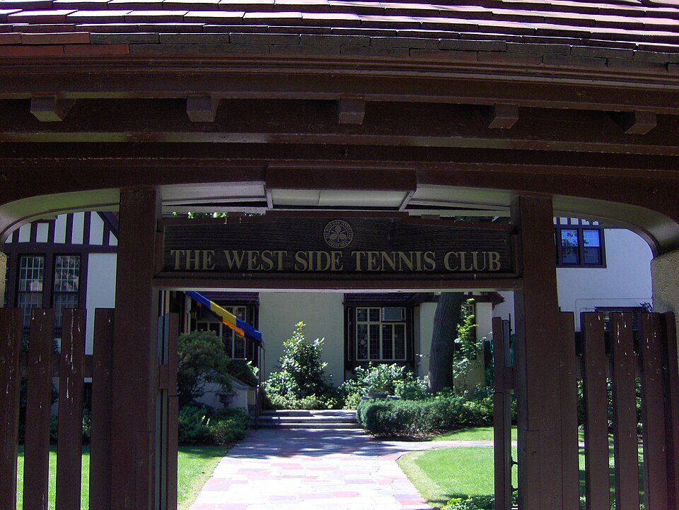 The gated entrance to the West Side Tennis Club, a wood sign reading The West Side Tennis Club over a brick path leading to the clubhouse.