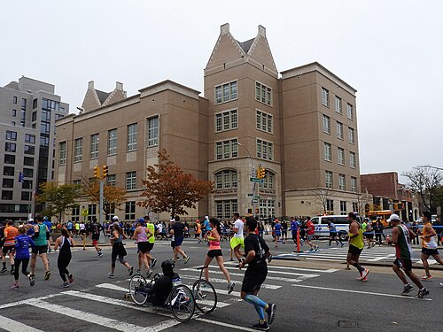 Fourth Avenue at Butler Street on marathon Sunday, runners crossing in front of the PS 133 school building.