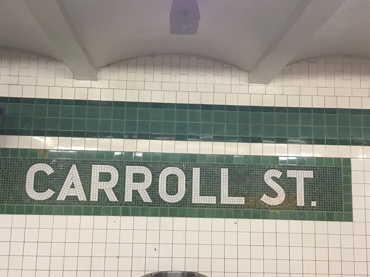 The Carroll Street station name in white and green mosaic on the platform wall.