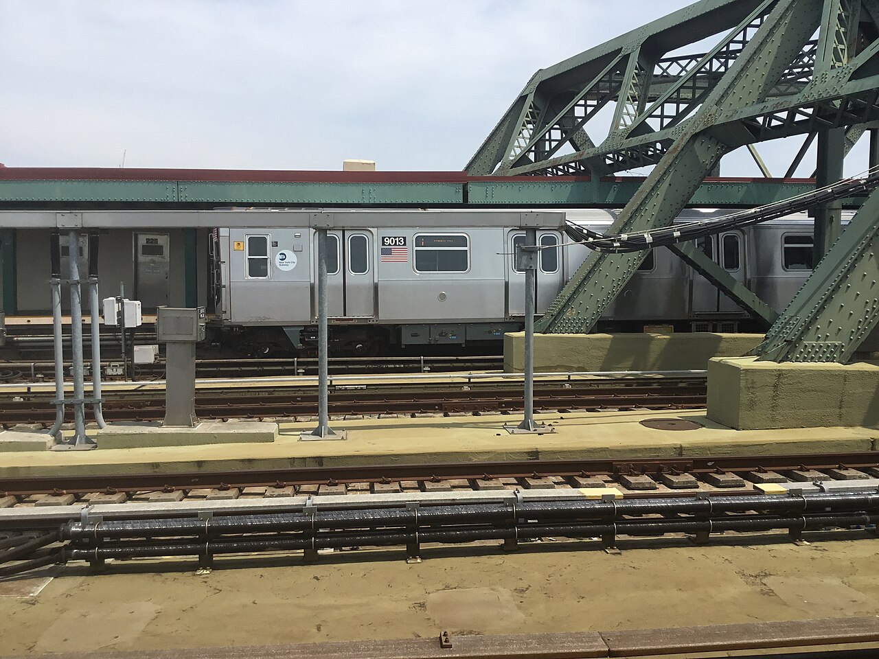 A train at Smith and Ninth Streets station, with the green steel of the Culver Viaduct alongside the platform.