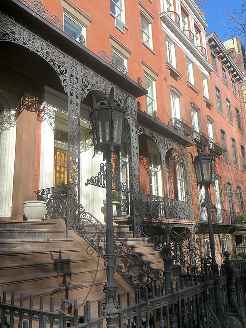 Two attached red brick houses, an arched cast iron veranda running the width of both stoops and a pair of lanterns flanking the entrance stairs.
