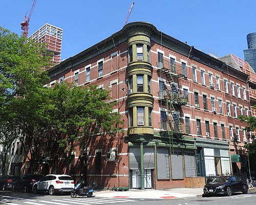 A corner tenement at Franklin and Freeman with a rounded bay and storefronts.