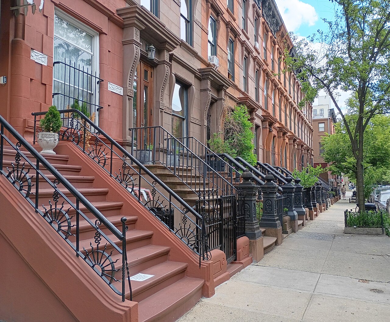 A brownstone row receding down the block, red painted stoops and iron railings.