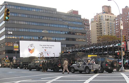 Tenth Avenue near the Lincoln Tunnel, army trucks lined up after the Veterans Day parade and a stacked car park behind them.