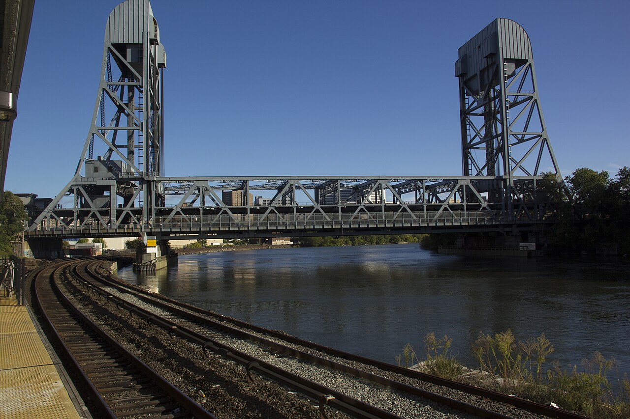 The Broadway Bridge from the Marble Hill side, a steel lift span between two towers, with railroad track in the foreground and the ship canal underneath.