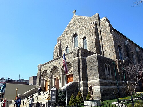 The Capuchin church at Broadway and Isham Street, grey stone with three arched doors above a flight of steps and a 1936 datestone on the corner.