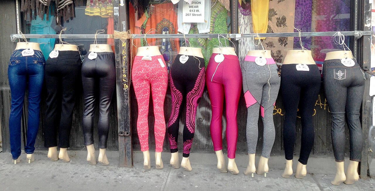 Nine pairs of leggings on mannequin legs hung on a rail outside a shop at 613 West 207th Street.