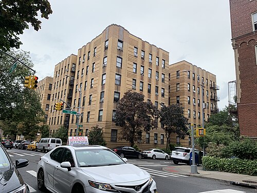 A six storey tan brick apartment house at 74th Street and 35th Avenue, seen from across the crossing.
