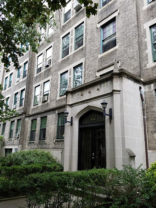 A doorway on 80th Street between 35th and 37th Avenues, a stone arch with two lanterns on a grey brick front, hedges along the path.