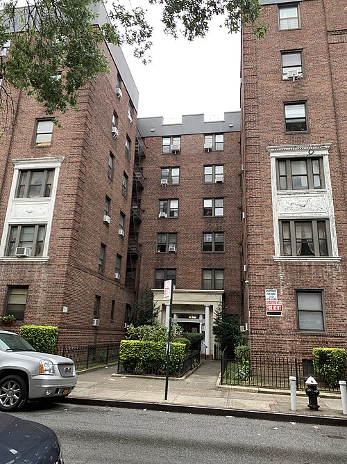 The entrance court of 35-46 74th Street, a white columned portico recessed between two brick wings.