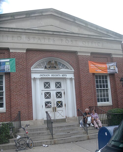 The post office on 37th Avenue, red brick with a stone pediment and Jackson Heights 11372 over the doors.