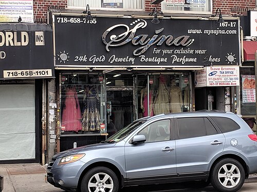 A storefront on Hillside Avenue selling gold jewelry and saris, mannequins dressed for weddings in the window and an SUV parked at the curb.