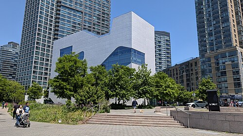 The Hunters Point Library on Center Boulevard, a pale concrete block with cut out windows, apartment towers standing around it.