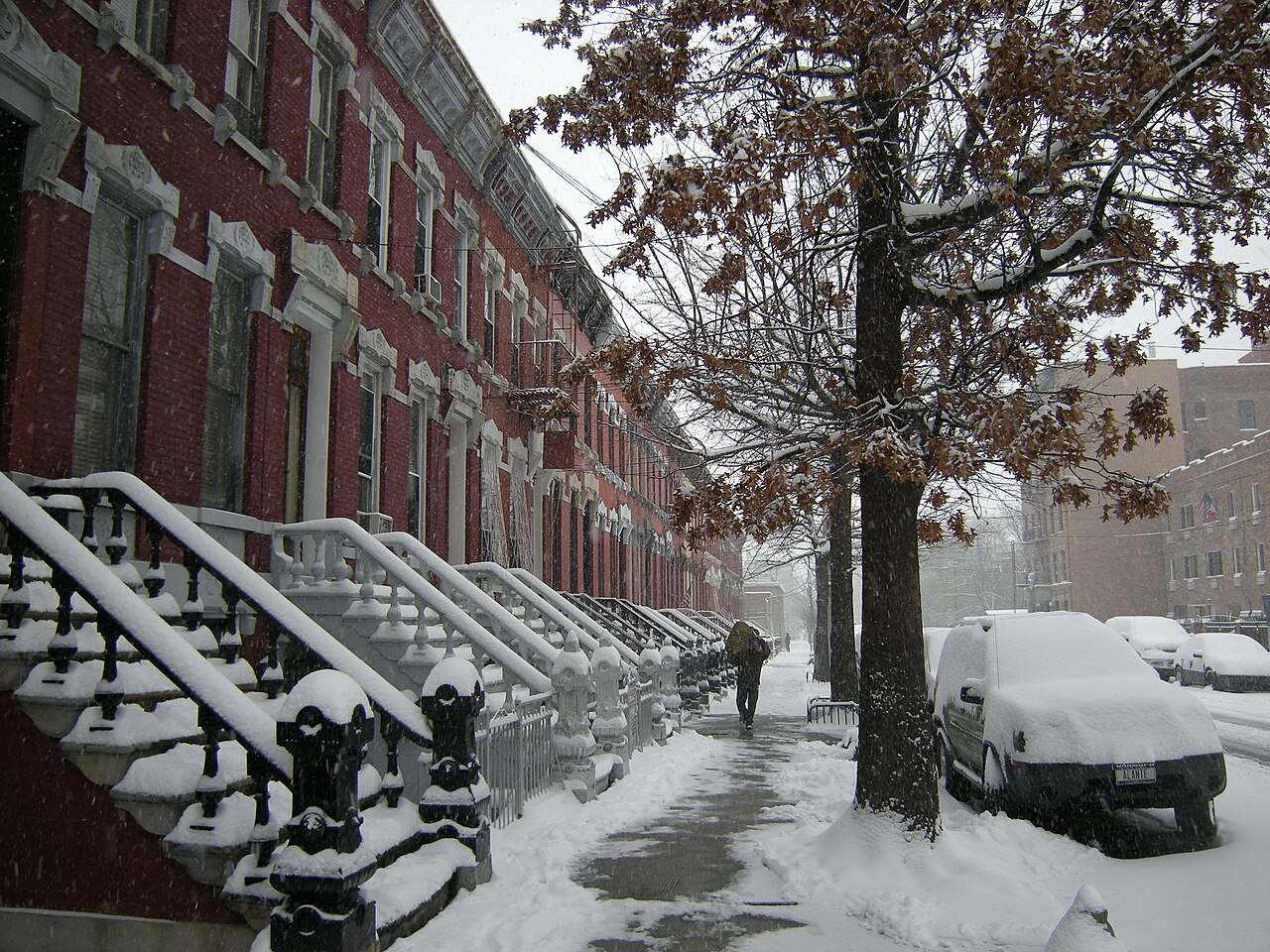 East 139th Street between Willis and Brook Avenues in snow, brick rowhouses with tall stone stoops the length of the block.