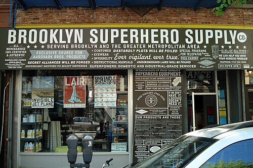 The Brooklyn Superhero Supply Co storefront at 372 Fifth Avenue, the whole front hand painted with the shop's list of goods, parking meters at the curb.