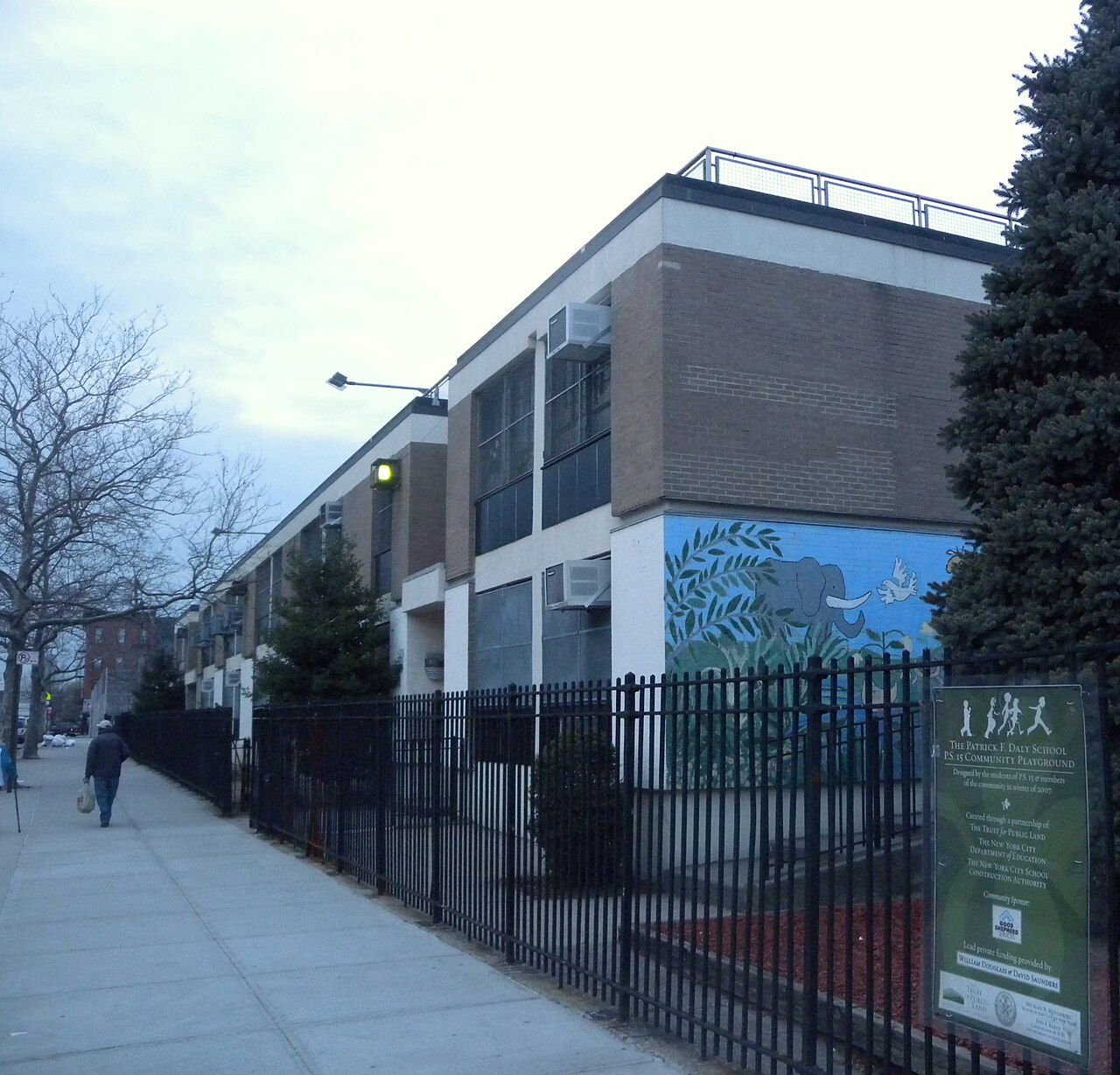 PS 15 on a winter evening, its playground behind an iron fence and a painted elephant on the end wall.