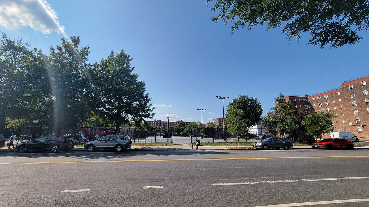 Clinton Street at Lorraine Street, with the ball courts of Bush-Clinton Playground behind the fence and a six story Red Hook Houses block on the right.