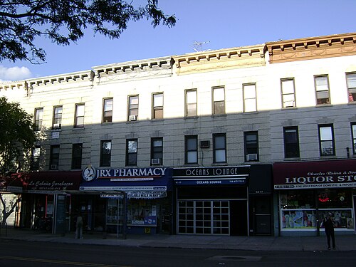 Fresh Pond Road storefront row under three story brick walk-ups.