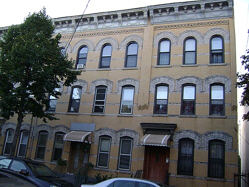 Mathews flats facade pair in ochre brick with white arched window heads.
