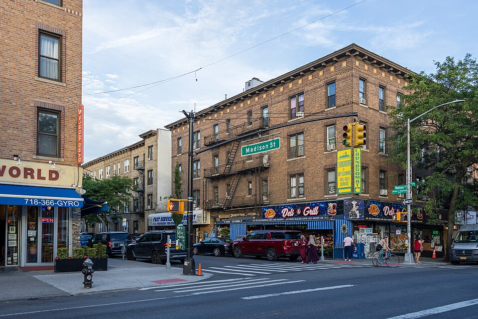 A brick corner deli and grill at Madison Street and Fresh Pond Road, the corner storefront street the production dressed.