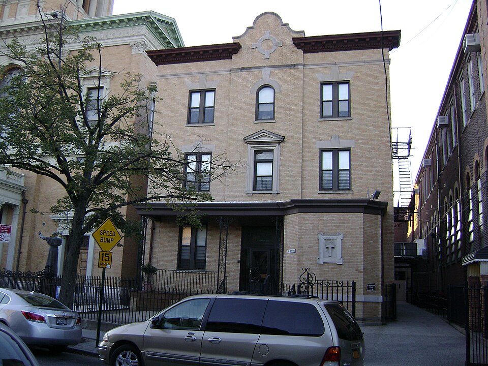 Catalpa Avenue at the St Matthias complex, yellow brick with a stepped gable, the church edge on the left and cars along the kerb.
