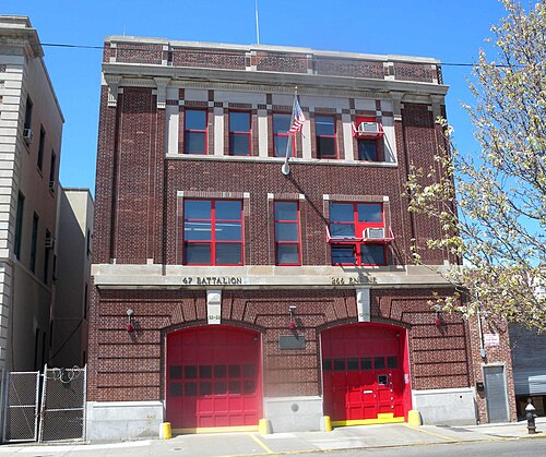 The Engine 266 and Battalion 47 firehouse near Beach 92nd Street, three storeys of brown brick with the company names cut into the stone over two red doors.