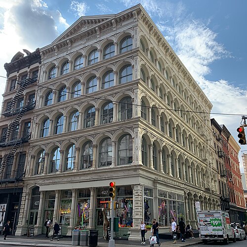 427 to 429 Broadway, a cream cast iron corner front with a pediment over the Broadway face and shops behind the columns at street level.