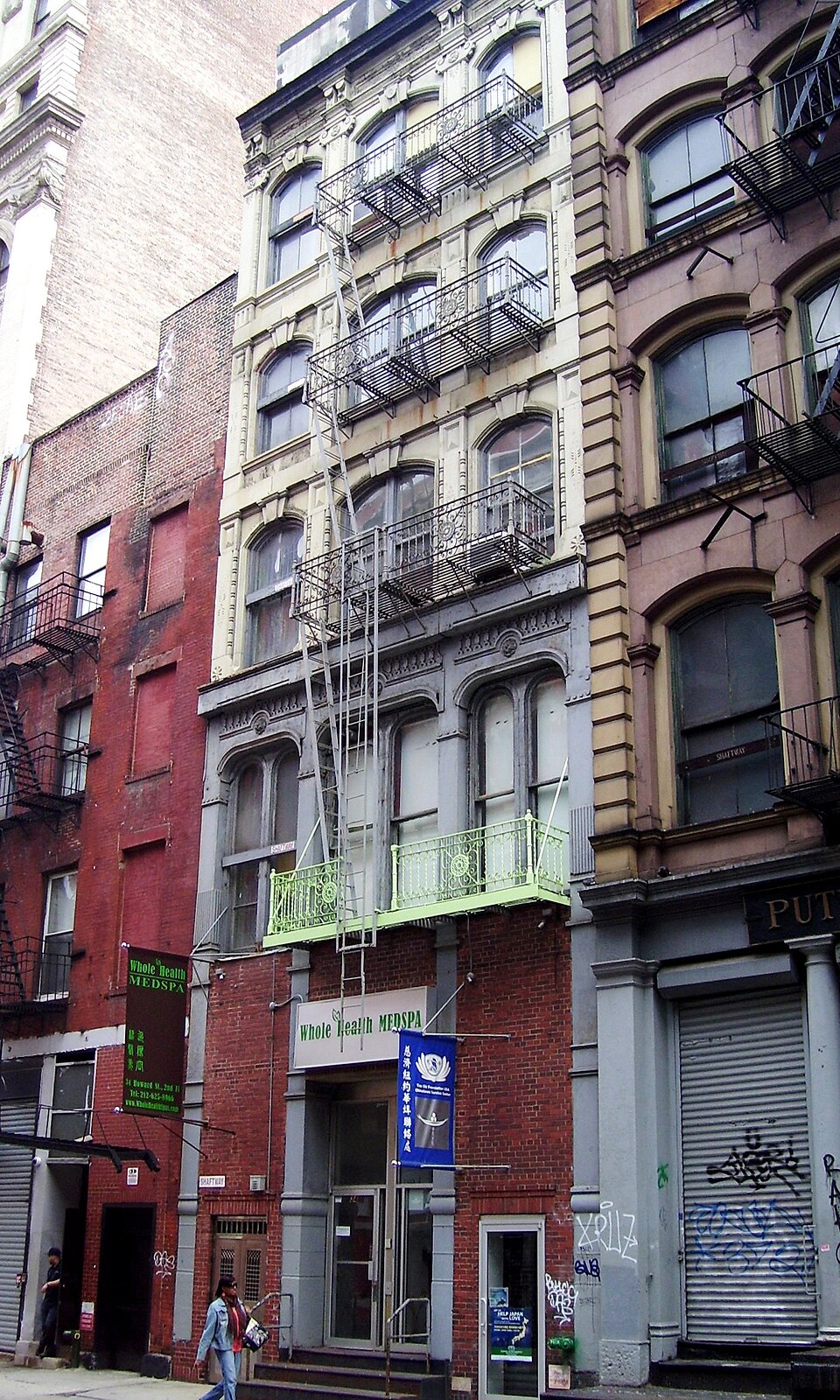Narrow fronts on Howard Street between Crosby Street and Broadway, with iron balconies and a fire escape running down the middle of one of them and a shopfront at street level.