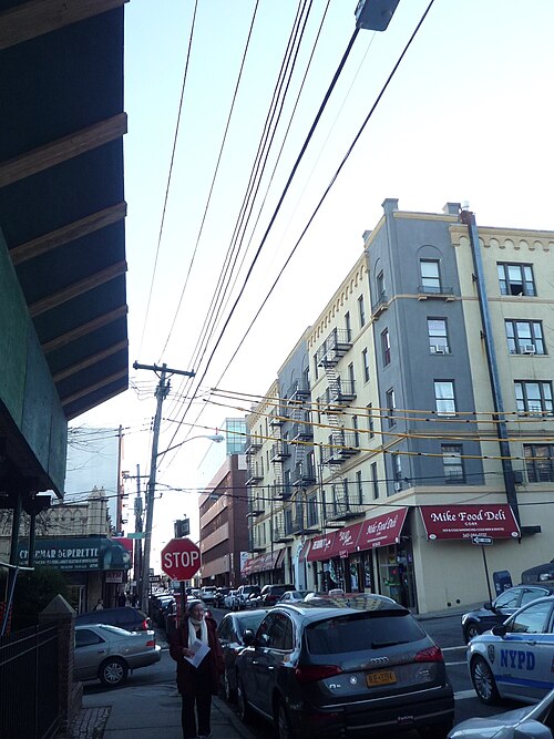 Stuyvesant Place climbing the hill past storefronts and a parked police car, the street curving out of sight ahead.