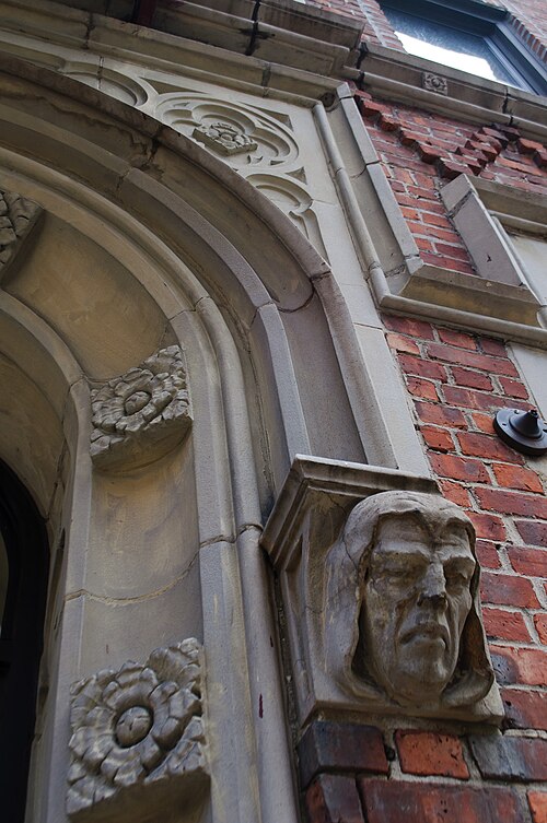 A carved stone entrance surround on a St. George apartment building, a sculpted face and floral rosettes set into red brick.