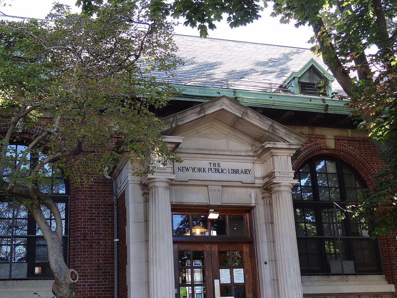 The entrance to the St. George branch of the New York Public Library, stone columns and a pediment under tree branches.