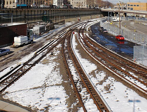 Staten Island Railway tracks fanning out toward St. George station in the snow, a parking lot alongside.