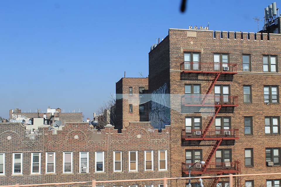 Brick apartment buildings on the north side of Queens Boulevard near 44th Street, seen from a 7 train window.