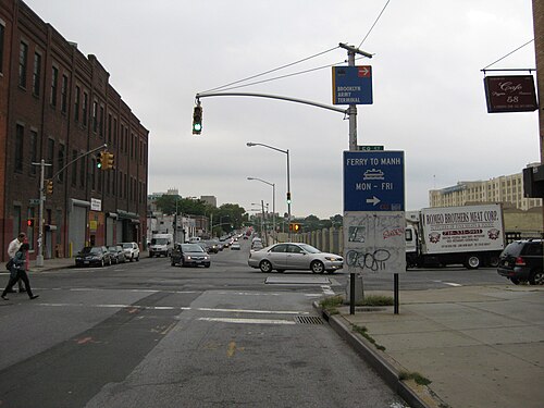 Third Avenue looking south at 58th Street, brick warehouses along the left and signs for the Brooklyn Army Terminal and the Manhattan ferry.