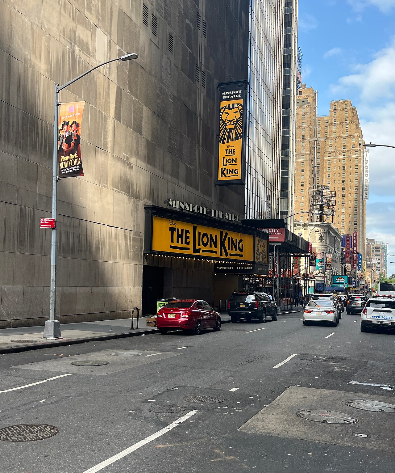 West 45th Street looking west from Broadway. The Minskoff Theatre marquee sits under the blank stone flank of One Astor Plaza, and the vertical signs for the Booth, the Schoenfeld and the Jacobs are further down the block.