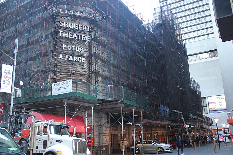 The Shubert Theatre at 225 West 44th Street under full scaffolding, its marquee lettering still readable above the sidewalk shed, with a contractor's truck at the kerb.