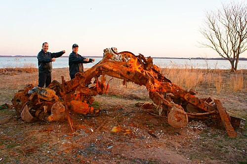 Tottenville Beach, with a large rusted wreck pulled up onto the sand and the bay behind it.
