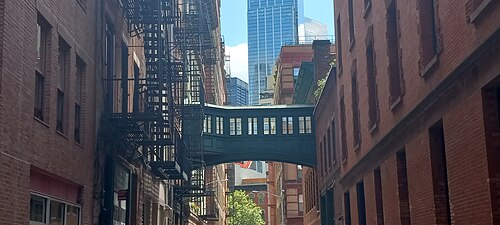Down the Staple Street alley, the skybridge framed by brick walls and fire escapes.