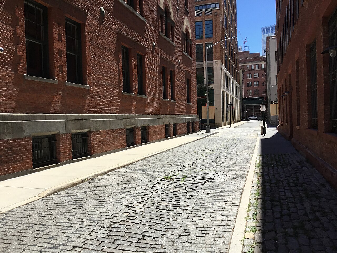 A cobbled Tribeca side street, red brick warehouses with granite loading-dock bases running the block.