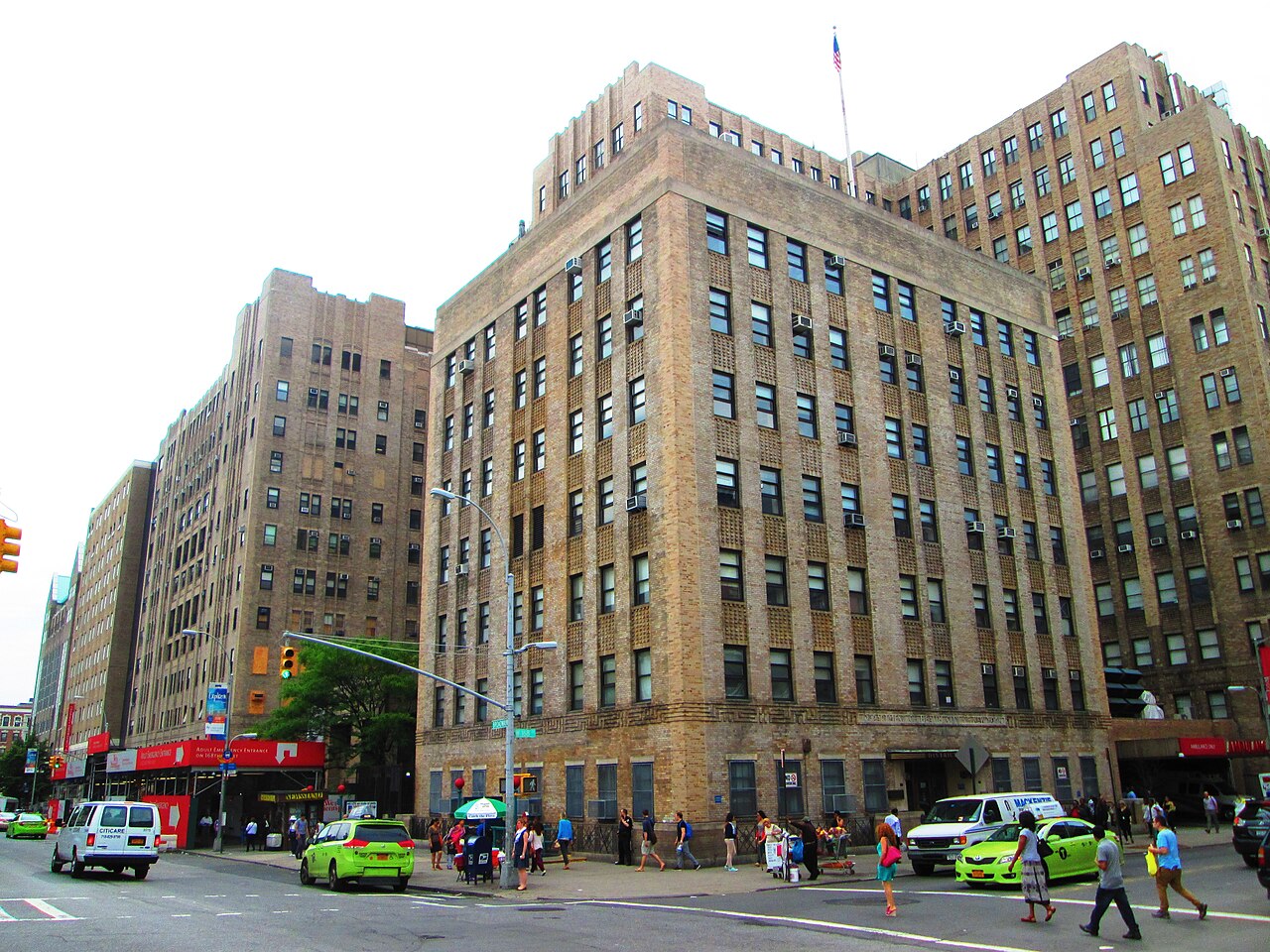 Broadway below West 168th Street, with the medical center's tan brick blocks on both corners and people crossing in front of them.