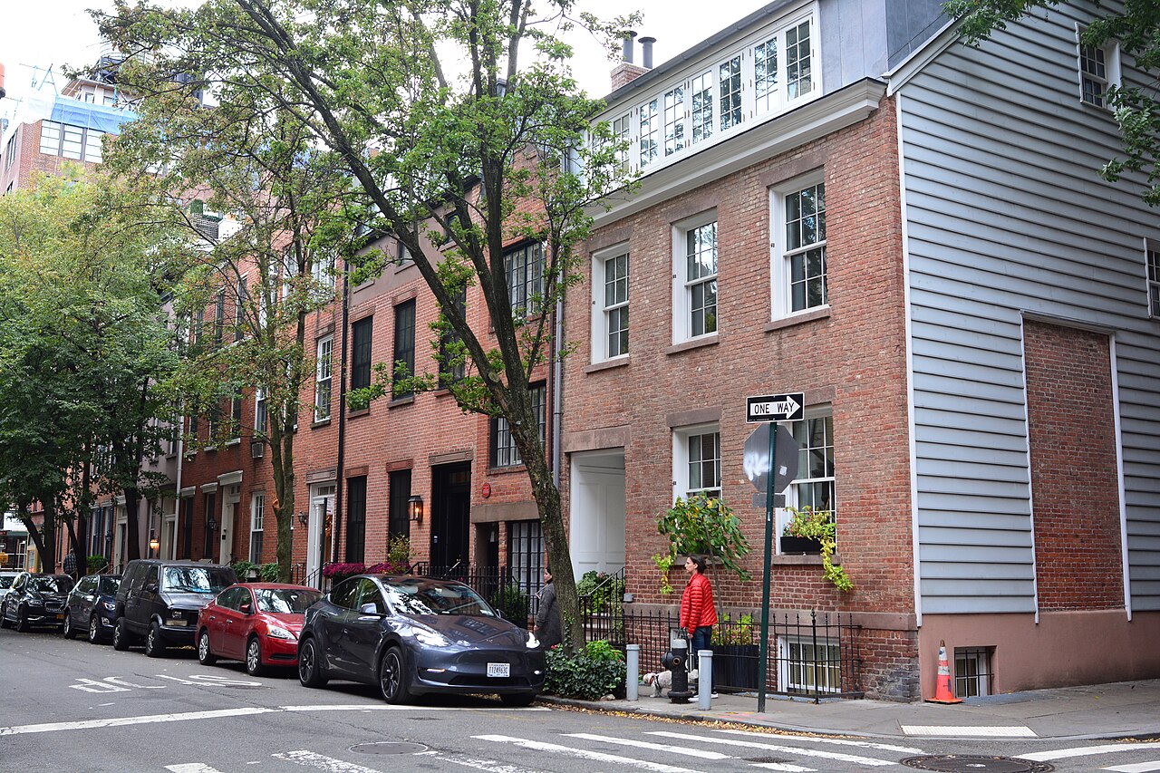 The west side of Bedford Street looking south from Commerce Street, a brick house with a clapboard flank at the corner and a row of brick fronts beyond it.