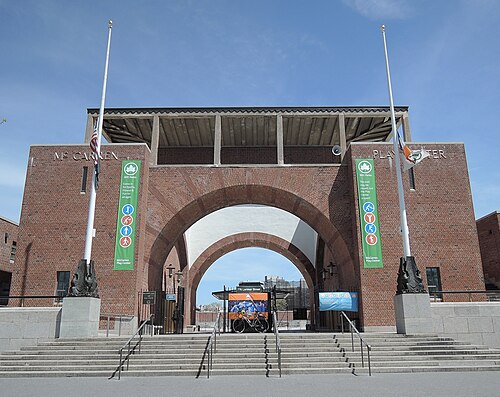 The brick arch at the Lorimer Street entrance to the McCarren Play Center, with McCARREN PLAY CENTER cut into the parapet and two flagpoles on granite bases.