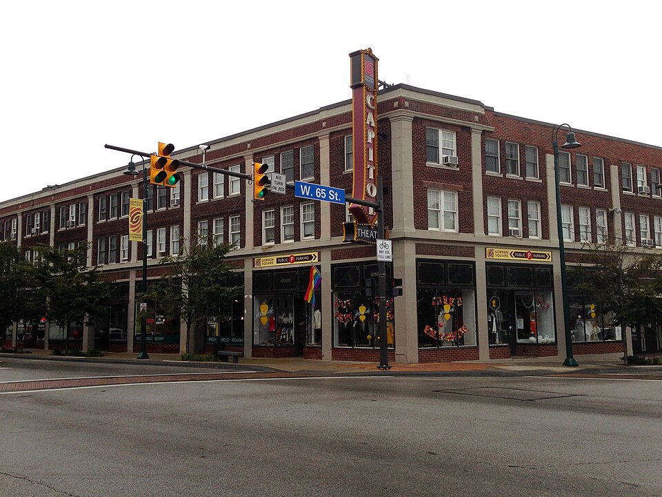 Detroit Avenue at West 65th Street, a brick corner building with the Capitol Theatre's marquee and storefronts along the sidewalk.