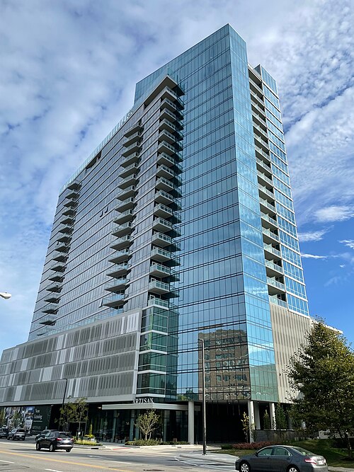 A modern glass and steel high rise residential building over a street level entrance.