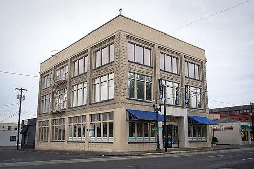 A three storey tan brick warehouse with a steel fire escape and rows of industrial sash windows, built in 1907.